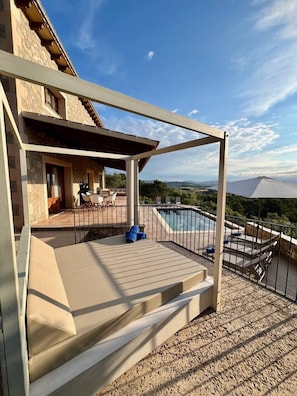 A covered outdoor area with a pool, a wooden deck, and a view of the landscape.