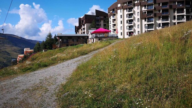 Ein modernes Hotel mit mehreren Etagen, einem Sessellift im Hintergrund und einem Weg zum Eingang.