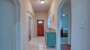A hallway with a wooden door, a blue dresser, and a bed in the background. - Luxury rental in great location (Spring)