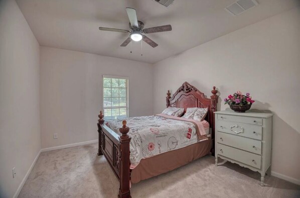 A bedroom with a bed, dresser, and ceiling fan.