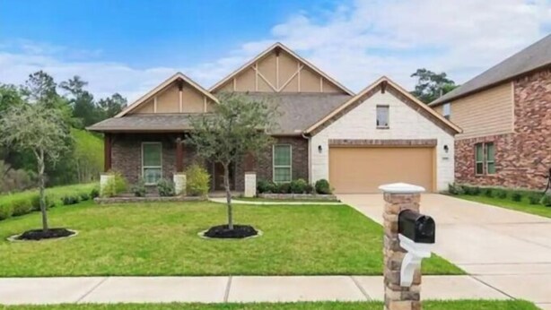 A two-story house with a stone facade, a front yard with a lawn and a small tree, and a mailbox. - Luxury rental in great location (Spring)
