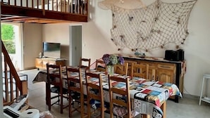 Un comedor con una mesa alta de madera y sillas, un lámpara colgante y una red decorativa en la pared.