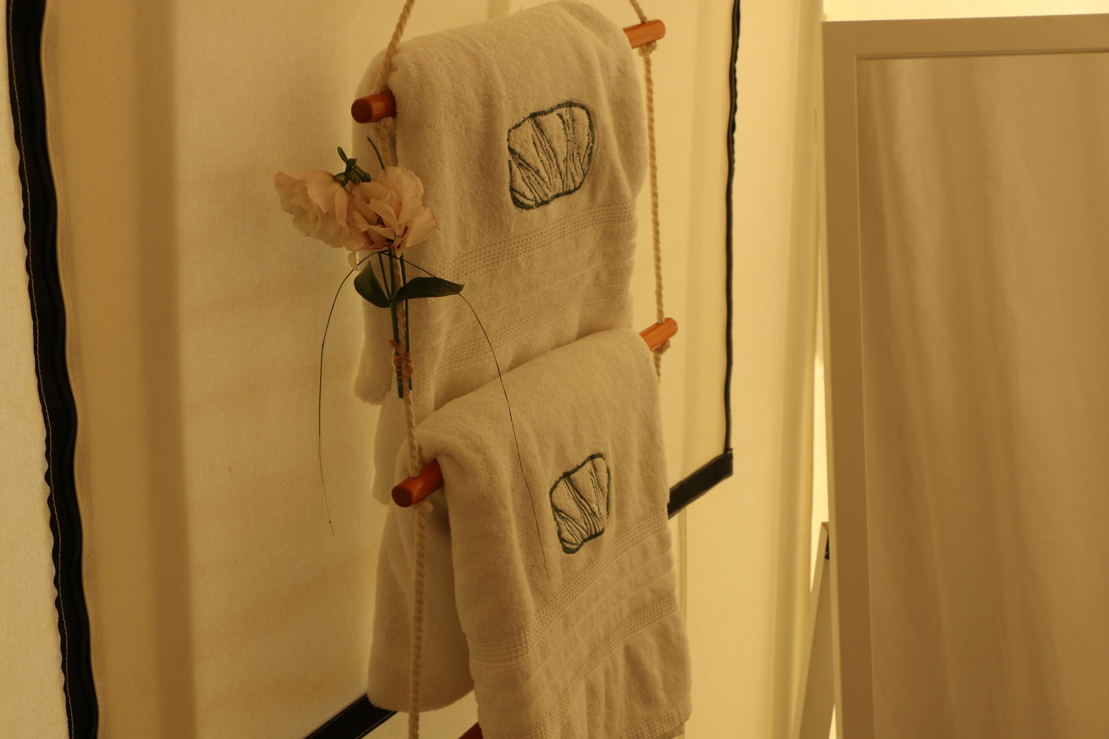 Un porte-serviettes avec deux serviettes et une fleur.