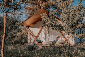 A tent-like structure with two lounge chairs, surrounded by trees and vegetation. - Salterra Glamping (Tequisquiapan)