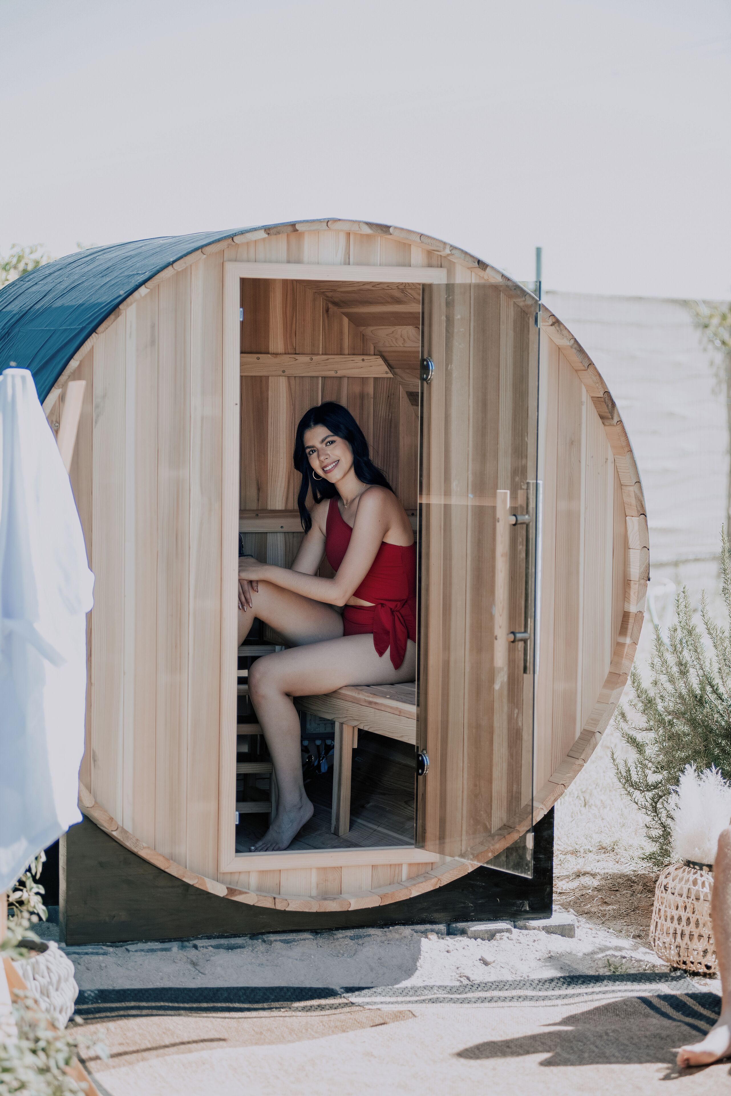 Una sauna de madera con techo curvo, un banco en su interior y vistas al mar.