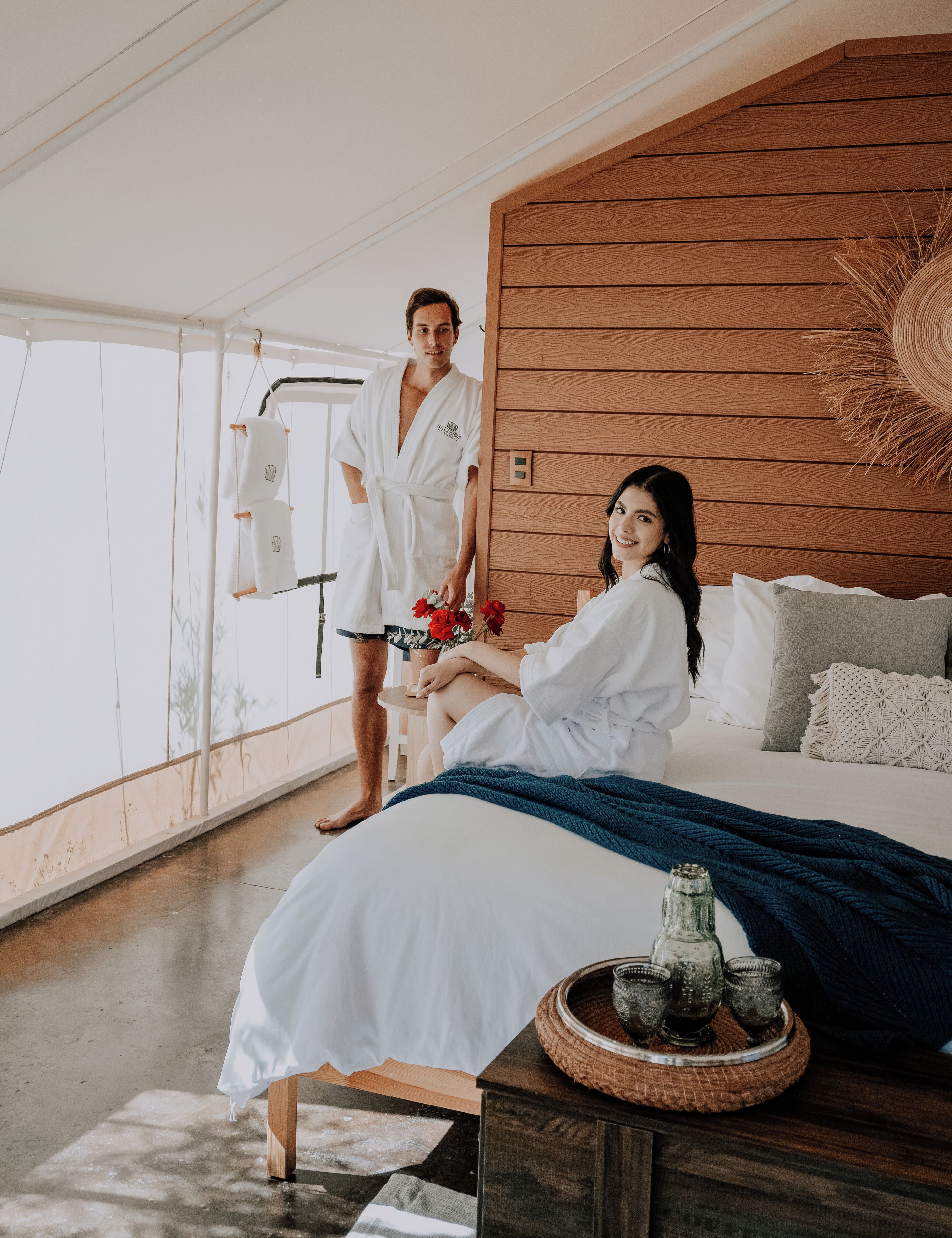 A modern bedroom with a large bed, wooden paneling, and a view of the outdoors.