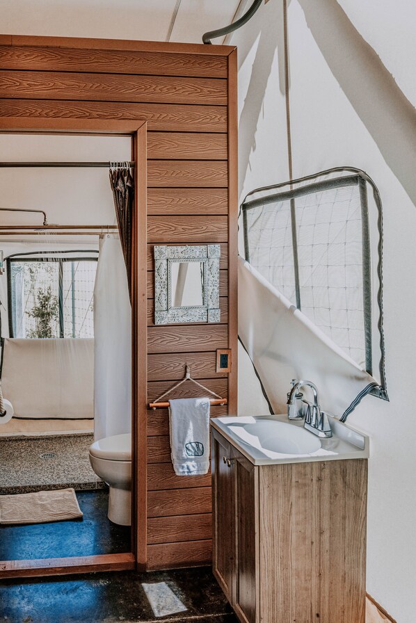 Un baño pequeño con tocador de madera, lavamanos y zona de ducha.
