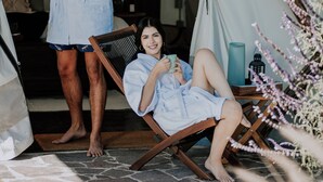 A tented accommodation with a person standing and another sitting on a chair, both in robes. - Salterra Glamping (Tequisquiapan)