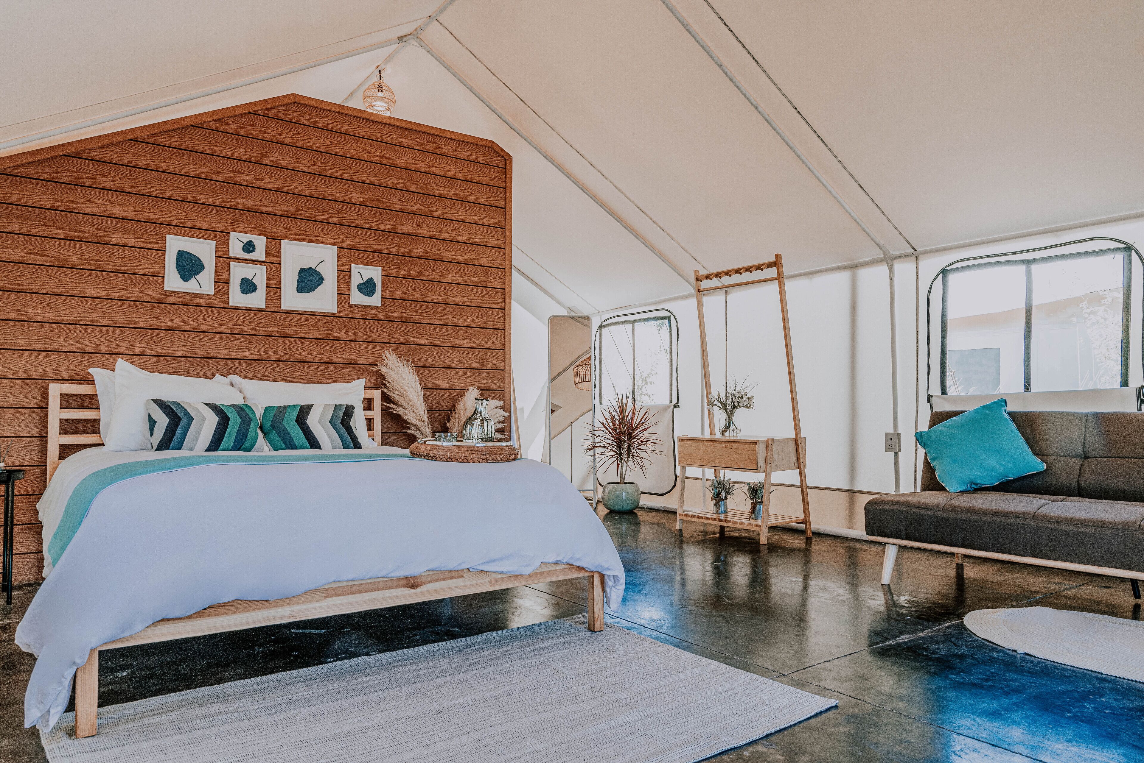 A spacious room with a large bed, a sofa, and a wooden accent wall with framed artwork.