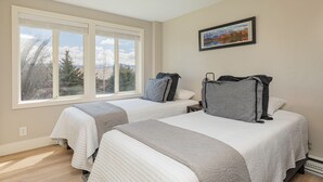 A bedroom with two beds, large windows, and a framed picture on the wall. - Gros Ventre B7: Newly remodeled, pristine condo in Teton Village (Teton Village)