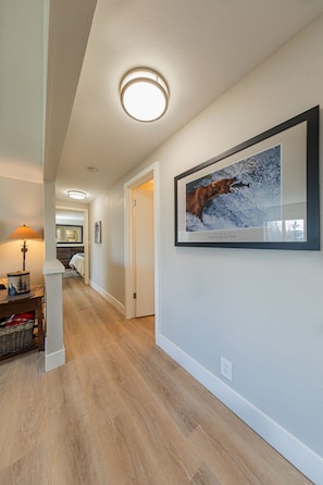 Stylish hallway leads to a serene bedroom with a comfortable bed and a cozy nightstand.