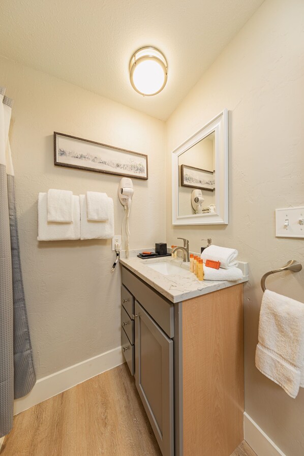 A bathroom with a sink, mirror, towel rack, and a hairdryer.