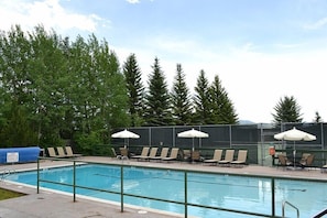 Relax by the pool surrounded by lush trees and comfortable lounge chairs.