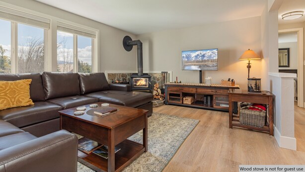 A cozy living room with a leather sofa, a wooden coffee table, a TV, and a wood stove. - Gros Ventre B7: Newly remodeled, pristine condo in Teton Village (Teton Village)