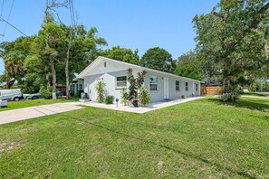 Uma casa térrea com jardim frontal, entrada por automóvel e vista para a rua.