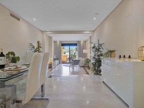A modern, well-lit hotel room with a dining area, a living space, and a view of the outdoors.