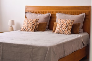 A bed with a headboard, pillows, and a bedside table with a lamp.