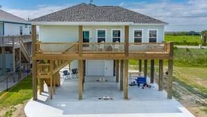 A two-story house with a balcony, a covered patio, and a garage. - 2-Minute walk to the beach! Dog & Kid Friendly! (Crystal Beach)