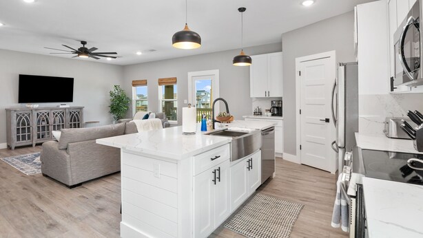 A modern kitchen with white cabinetry, a central island, and pendant lighting. - 2-Minute walk to the beach! Dog & Kid Friendly! (Crystal Beach)