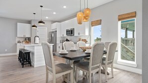 A modern kitchen with white cabinets, a central island, and a dining area with six chairs. - 2-Minute walk to the beach! Dog & Kid Friendly! (Crystal Beach)
