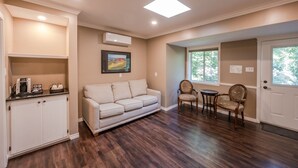 A living room with a sofa, chairs, a coffee station, and a window with a view. - Munson Mountain Estates (Penticton)