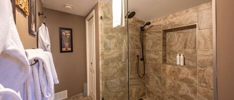 Une salle de bain moderne avec une douche à parois de verre, des carreaux de marbre et un porte-serviettes avec des serviettes blanches.