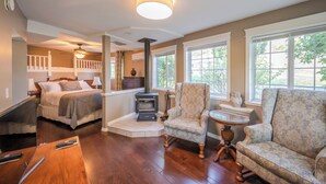 A cozy room with a bed, a fireplace, a sofa, and a chair. - Munson Mountain Estates (Penticton)