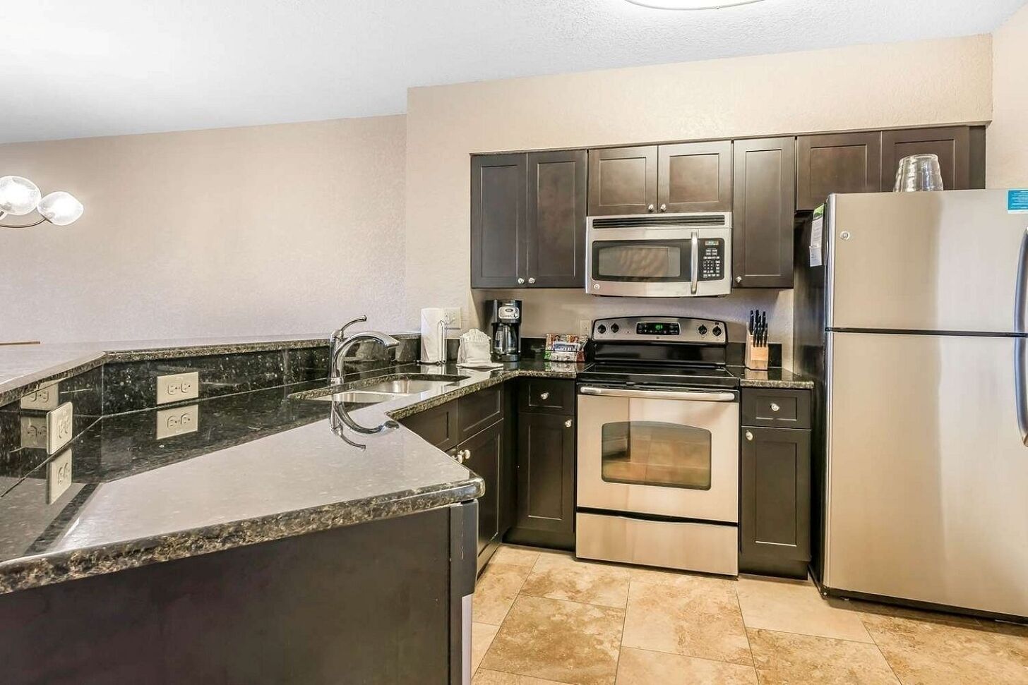 A kitchen with a granite countertop, stainless steel appliances, and dark cabinetry.