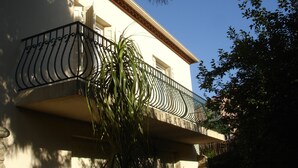 Ein weißes Gebäude mit einem Balkon und einem schmiedeeisernen Geländer.