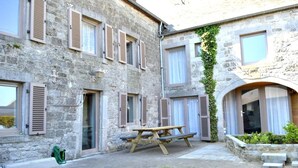 A stone building with multiple windows, a wooden bench, and a garden area. - Charming holiday home - 10 min from Durbuy (Durbuy)