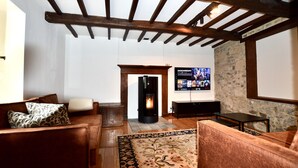 A cozy living room with a fireplace, wooden beams, a stone wall, and a television. - Charming holiday home - 10 min from Durbuy (Durbuy)