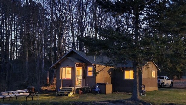 A cabin with a porch, a dock, and a reflection in the water. - Cabin right on the water! All bikers, skiers, fisherman, and more welcome! (Cable)