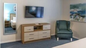 Una habitación de hotel con una cama, un aparador, un televisor y un cuadro en la pared.