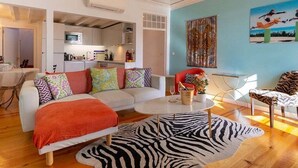 A modern living room with a sofa, a zebra-patterned rug, and a dining area with a table and chairs.