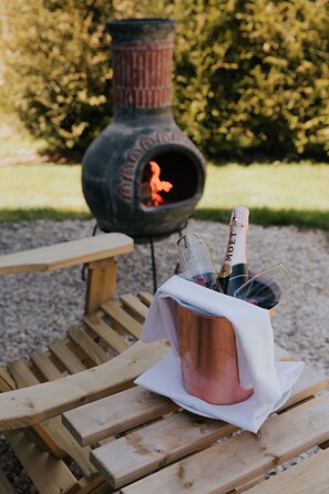 A wooden table with a copper bucket containing a bottle of champagne and glasses.