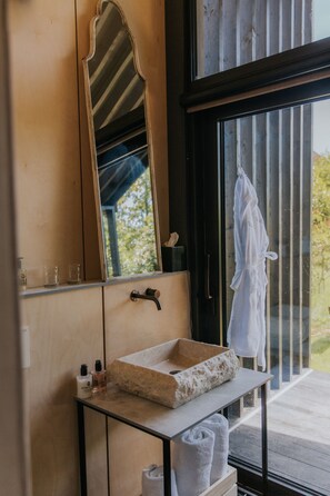 A bathroom with a wooden vanity, a mirror, a sink with a stone basin, and a towel rack.