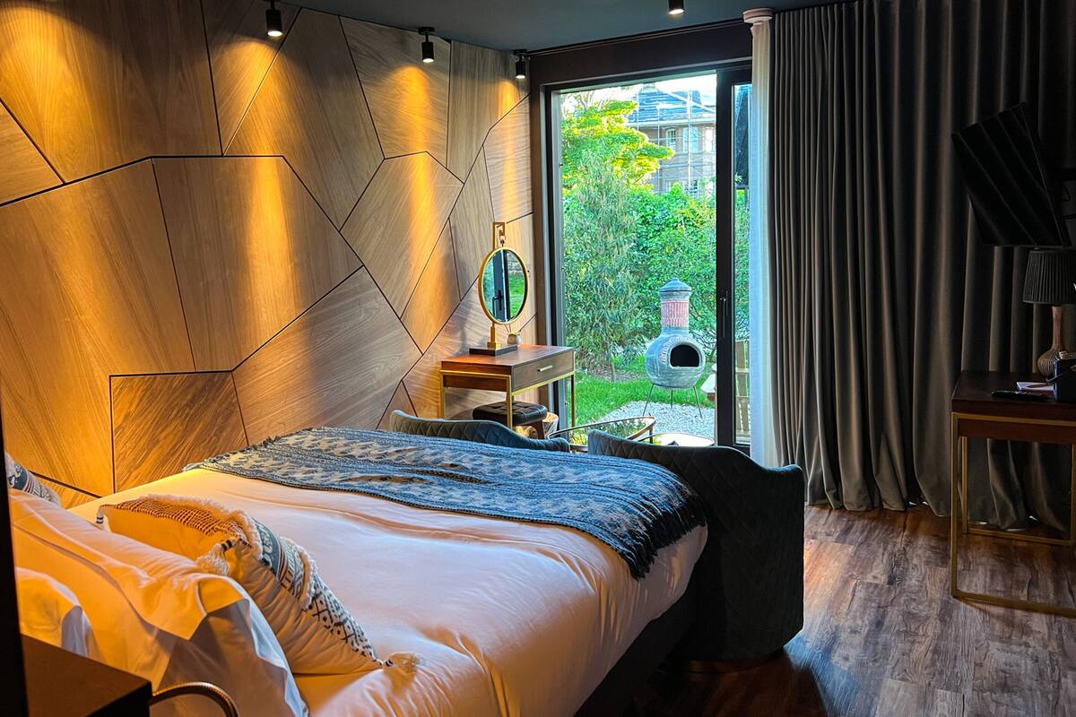 Un dormitorio moderno con una cama grande, una mesita de noche con espejo y vistas al exterior.