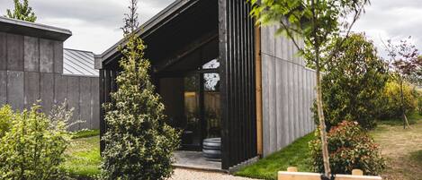 A modern building with a sloped roof, a gravel pathway leading to the entrance, and a wooden fence surrounding the property.