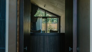 Vista per una porta oberta a un espai interior amb finestra que dona a un jardí.