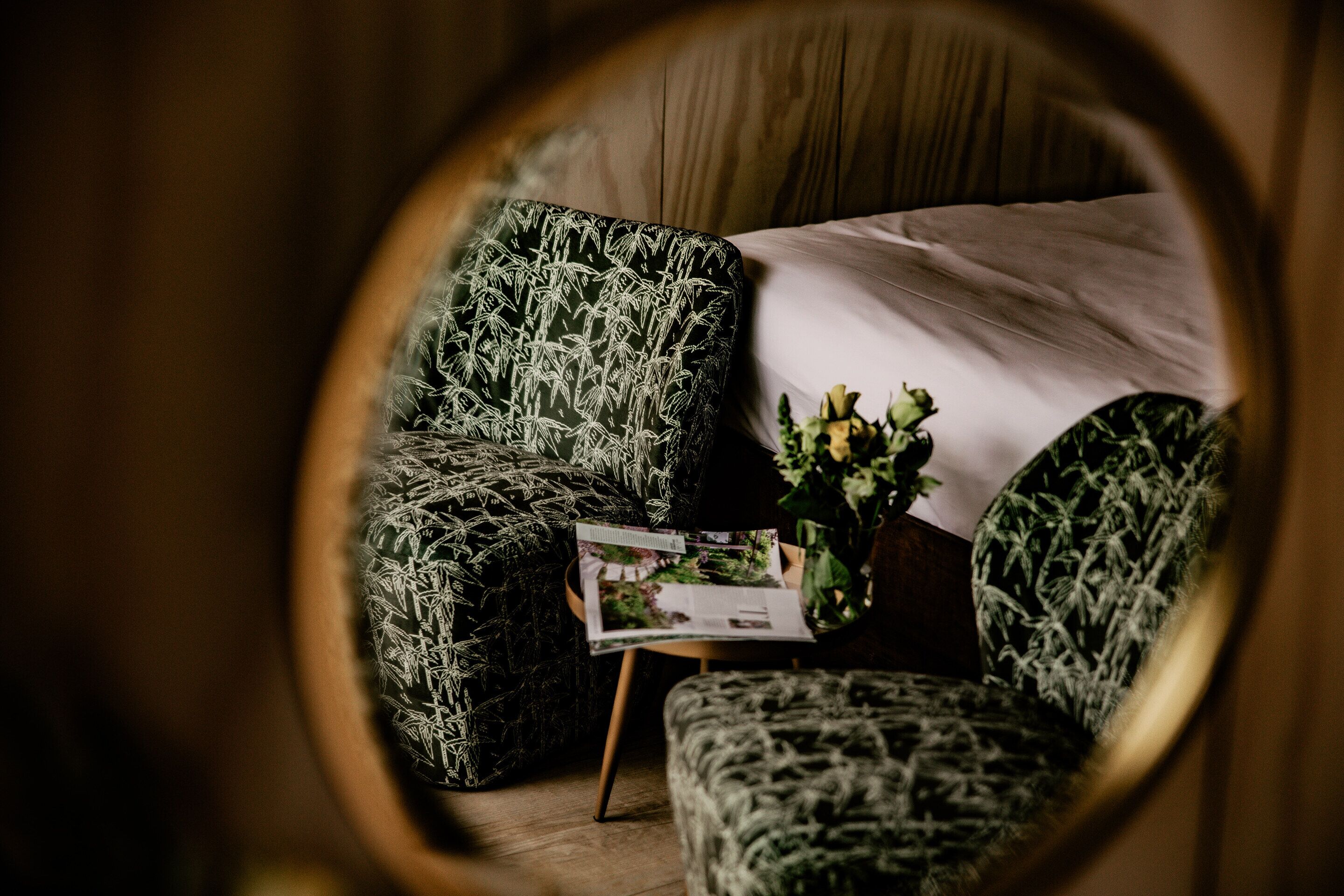 A bedroom with a bed, a chair, and a small table with a magazine.