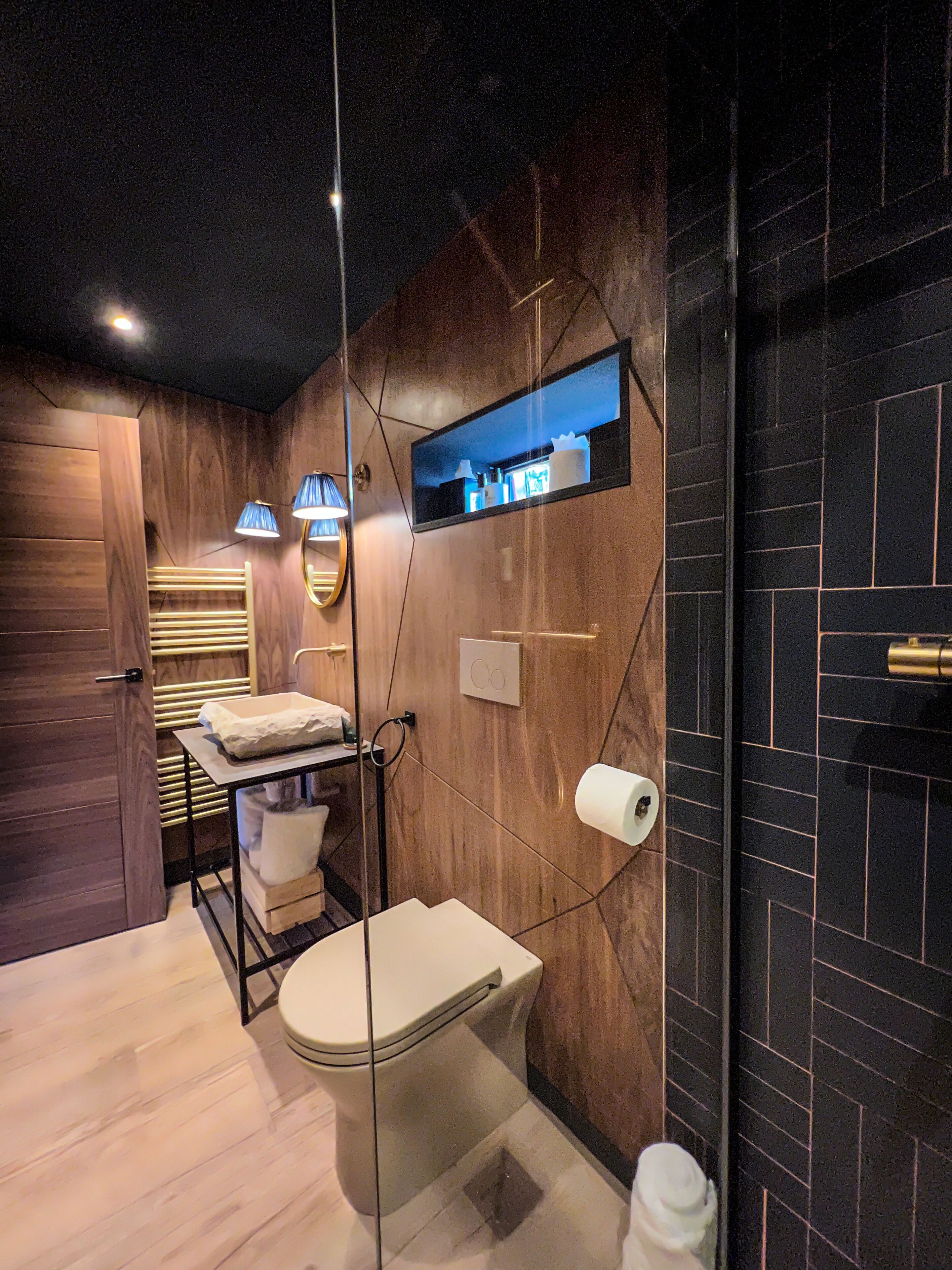 Ein modernes Badezimmer mit Holzwand, Toilette, Waschbecken und Spiegel.