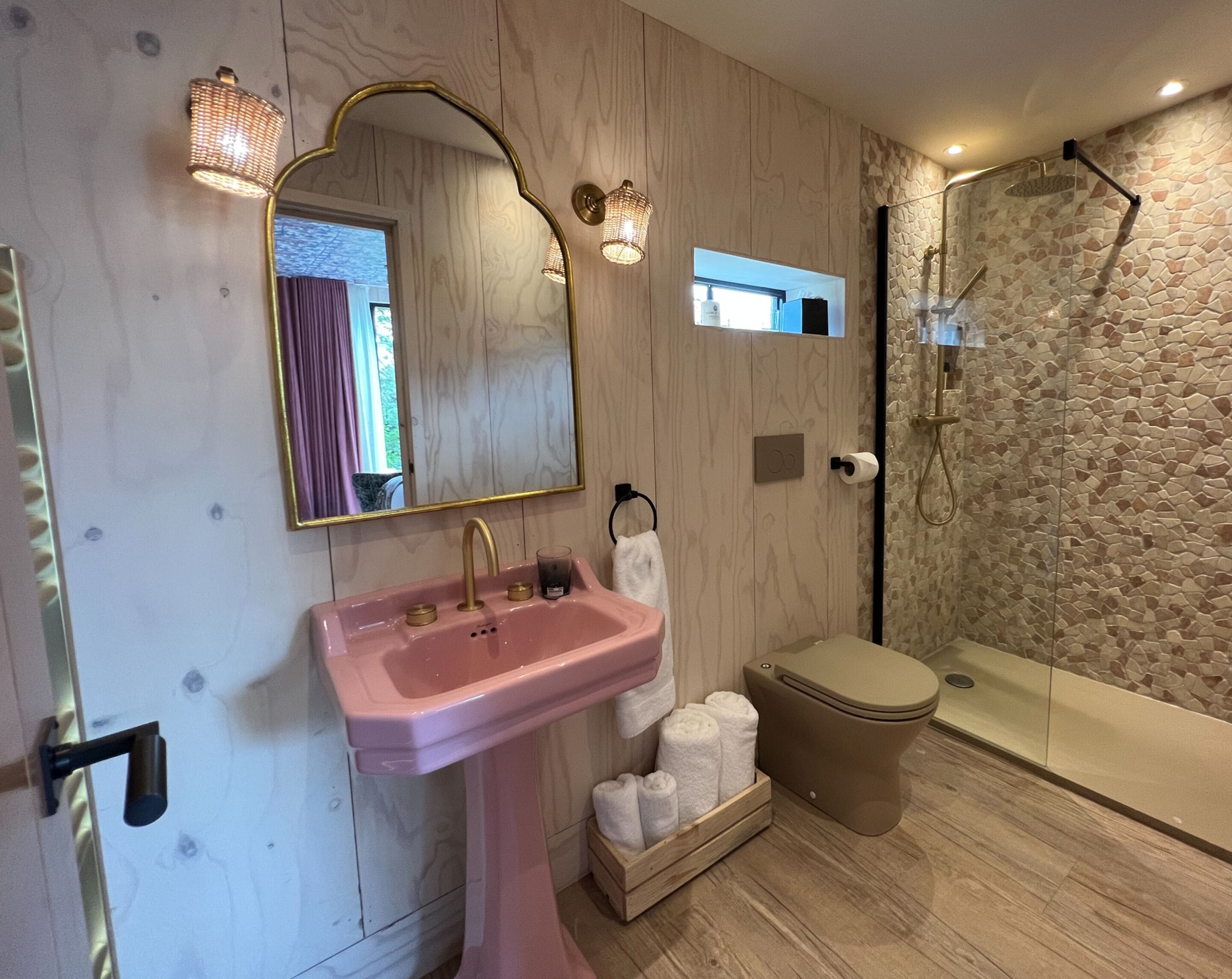 A bathroom with a pink sink, a toilet, and a shower area.