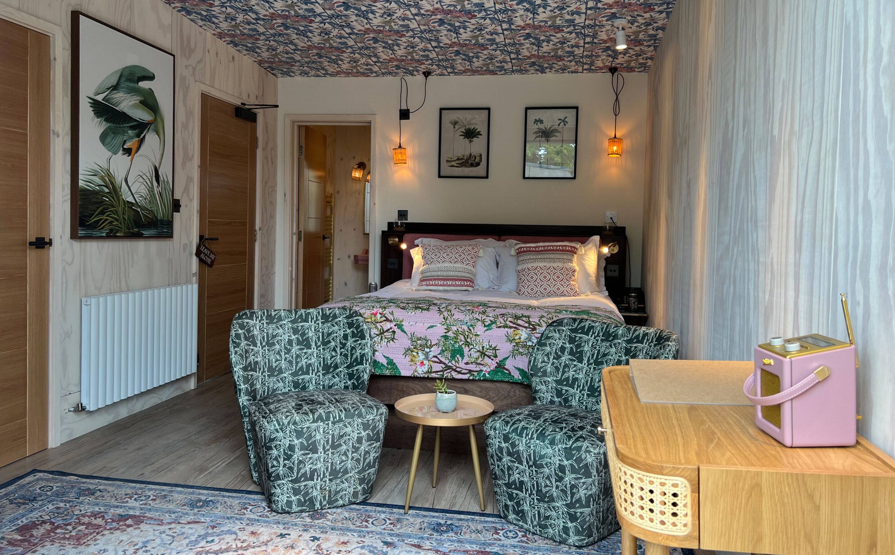 Een slaapkamer met een bed, een tafeltje, een stoel, een bureau en een radiator.