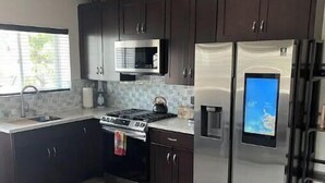 A modern kitchen with dark cabinets, stainless steel appliances, a microwave, a stove, and a refrigerator.