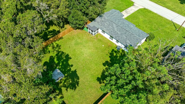 An aerial view of a residential property with a fenced yard, a house with a sloped roof, and surrounding trees. - Renovated 3BR, Fenced Yard, Brandon | Sleeps 8, 20 Min to Tampa, Monthly OK (Brandon)
