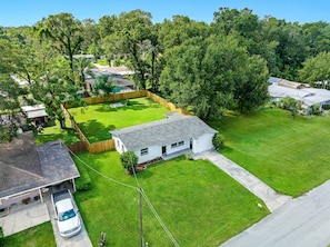 A residential property with a fenced backyard, a detached garage, and a single-story house with a sloped roof.