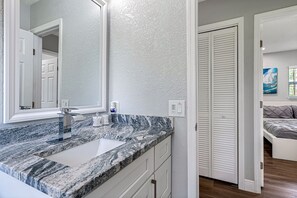 A bathroom with a granite countertop, a mirror, and a white door.