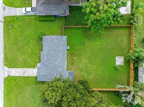 En bostadsfastighet med en asfalterad uppfart, en gräsmatta, en inhägnad trädgårdsyta och ett hus med ett sluttande tak.