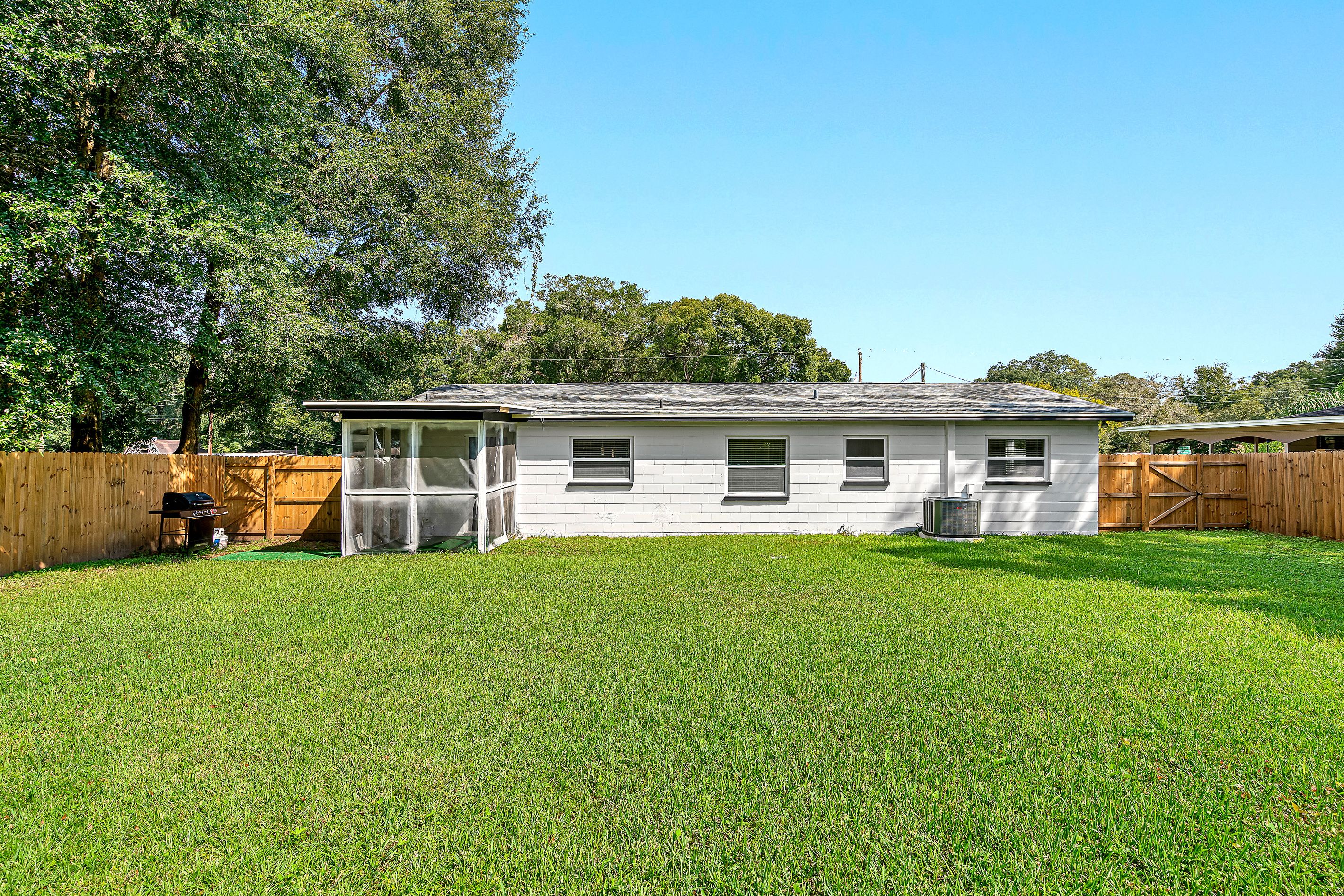 A single-story house with a fenced backyard, a covered porch, and a visible air conditioning unit.