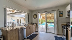 Une cuisine moderne avec des meubles en bois, des appareils en acier inoxydable et une vue sur une piscine.